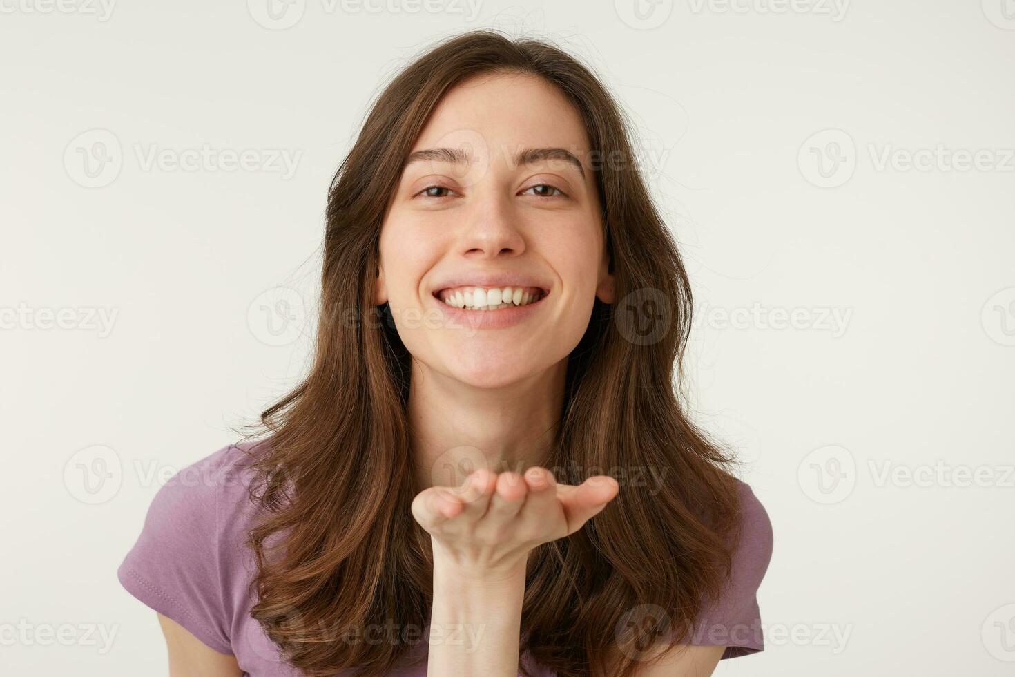 Portrait of lovely sweet girl with modern hairdo blowing air kiss with smile one palm at camera isolated on white background, demonstrate feelings to her boyfriend photo