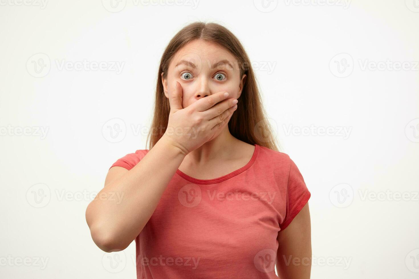 Bemused young white-headed female keeping raised palm on her mouth and rounding amazedly eyes while posing against white background in casual clothes photo