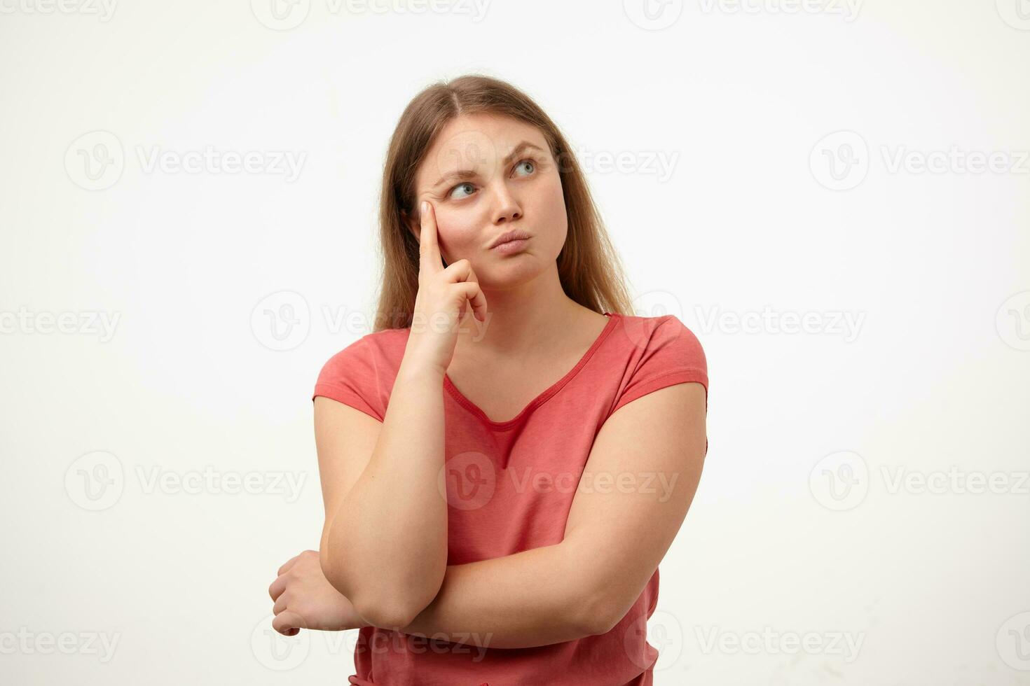 Puzzled young pretty blonde woman with casual hairstyle twisting her mouth while looking pensively aside and leaning head on raised hand, posing over white background photo