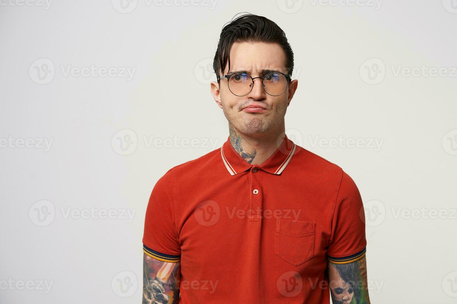 Geek making a dissatisfied expression, looking away through glasses, displeased grimace,polo shirt buttoned under the throat, isolated over white background. photo