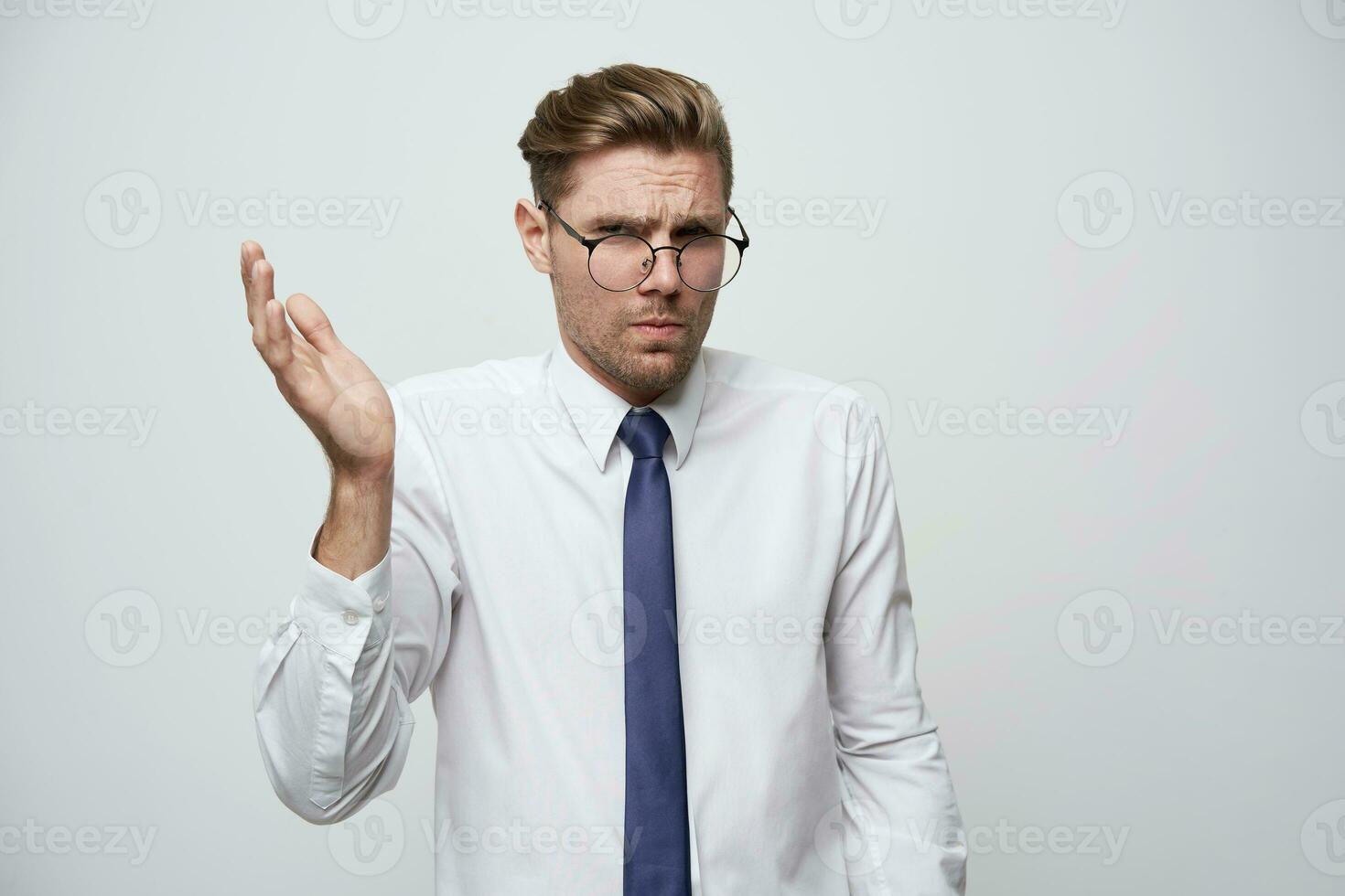What is the problemStudio shoot of young businessman showing misunderstanding,the absurdity of the situation, with stylish haircut, glasses,unshaven,dressed white shirt and blue tie, white background photo