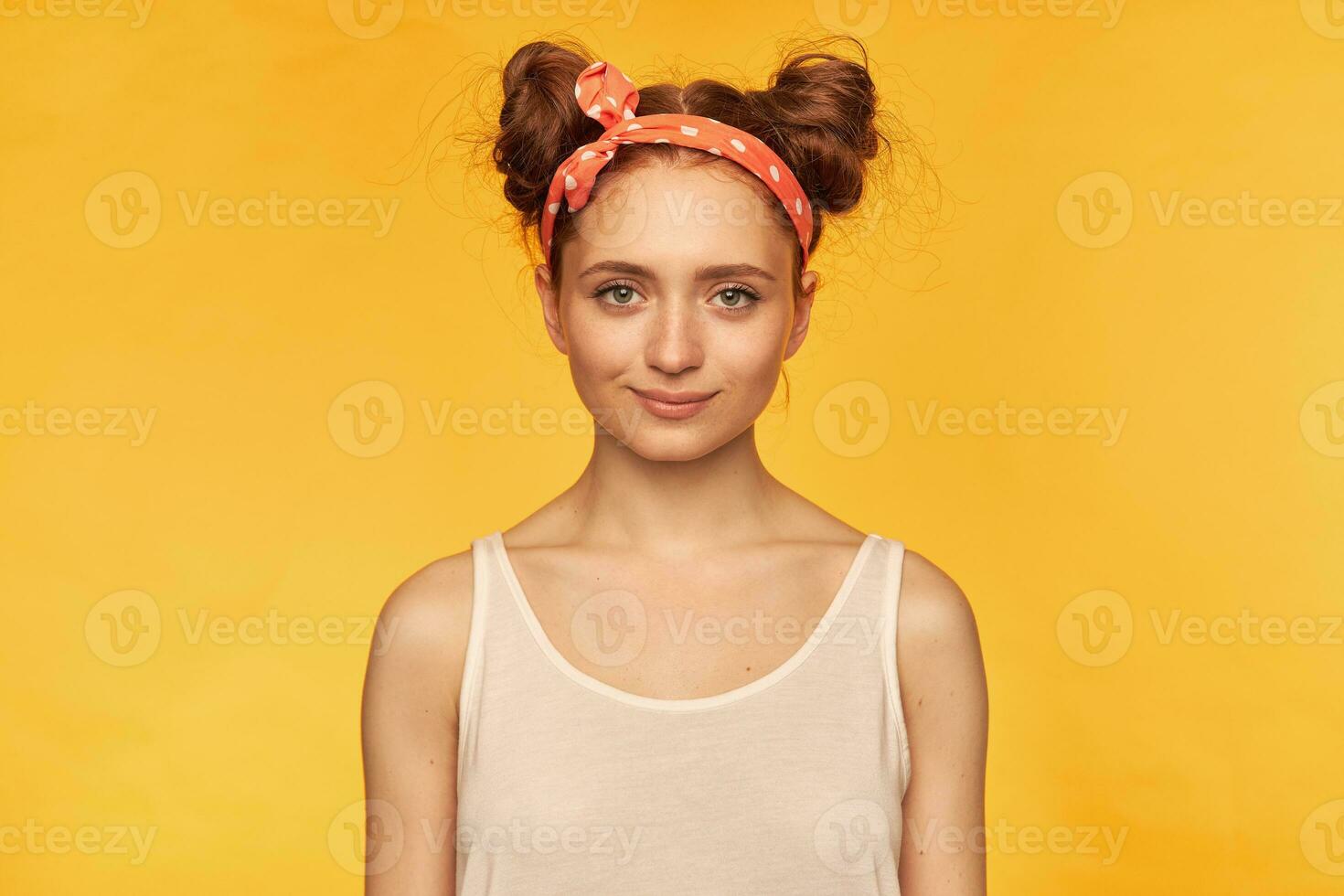 joven dama, bonito jengibre mujer con dos bollos vistiendo blanco tanque parte superior y rojo adorado banda para el cabello. mirando seguro, esperando para algo. acecho a el cámara aislado terminado amarillo antecedentes foto