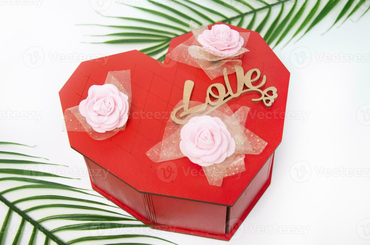 Heart shaped gift box with pink roses and palm leaf on white background photo
