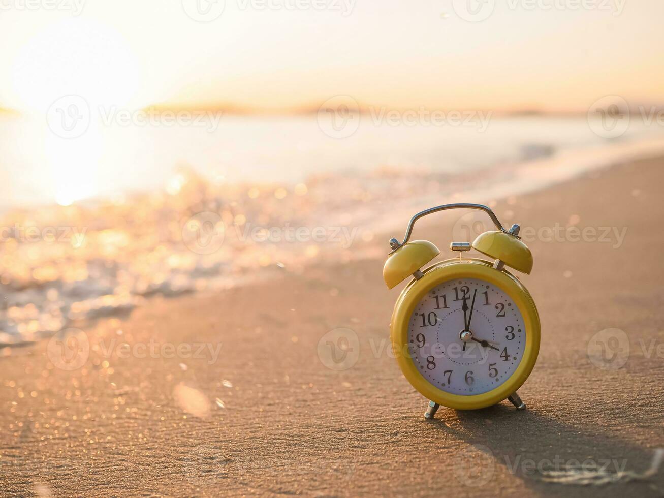 Yellow alarm clock on the beach in the sunset time. The concept about Time to summer, Travel, Vacation and Relaxation photo