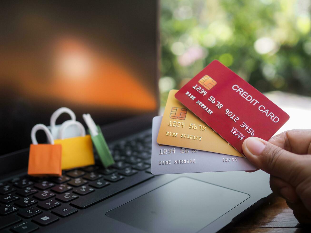 Woman hand holding credit cards and shopping bags on a laptop keyboard. Concepts about online shopping that offers home delivery photo