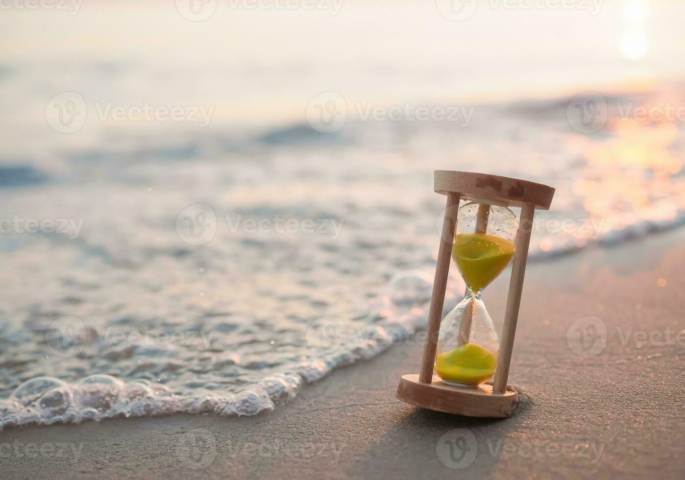 Hourglass on the beach in the sunset time. The concept about countdown to Summer, Travel, Vacation and Relaxation. photo