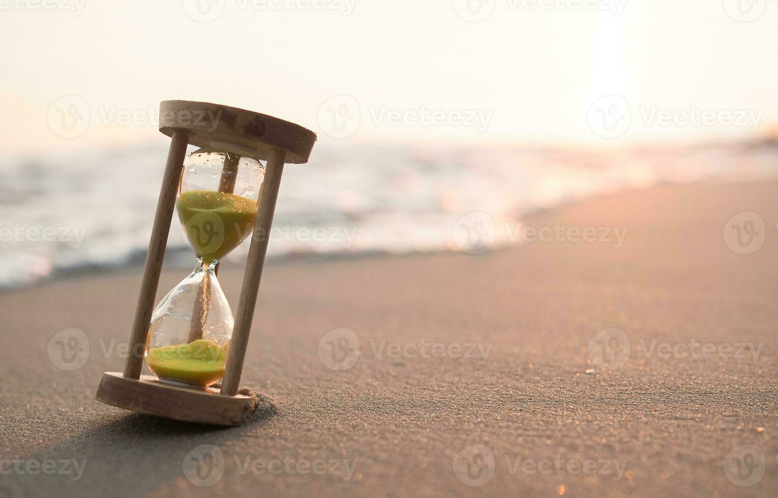 Hourglass on the beach in the sunset time. The concept about countdown to Summer, Travel, Vacation and Relaxation. photo