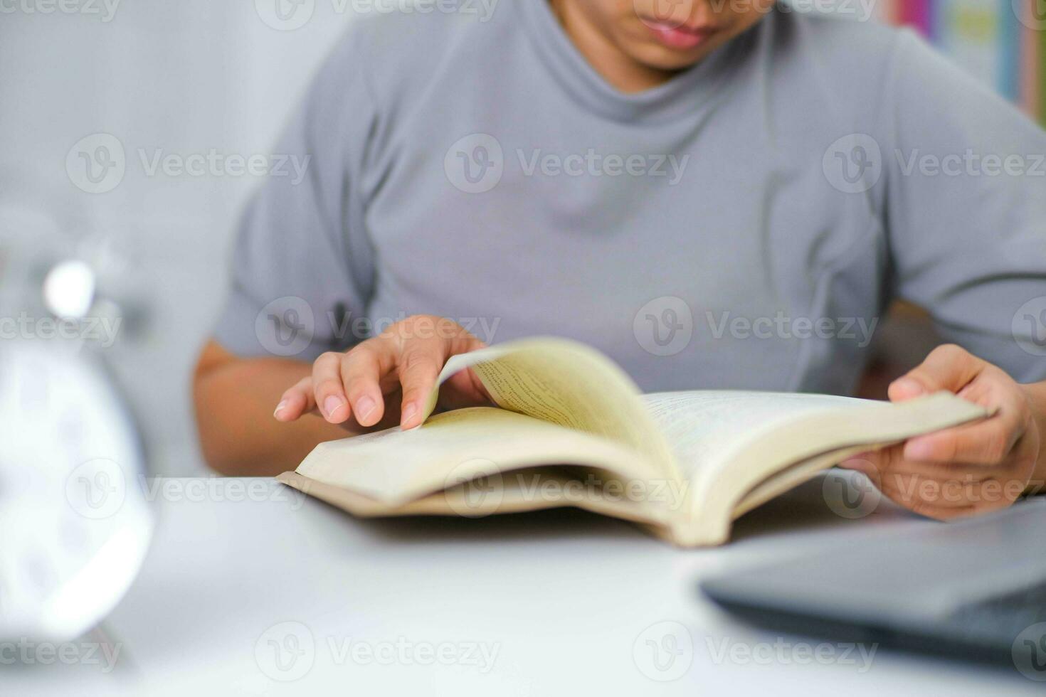 Closeup image of Asian woman sitting at a table reading a book in the living room. photo