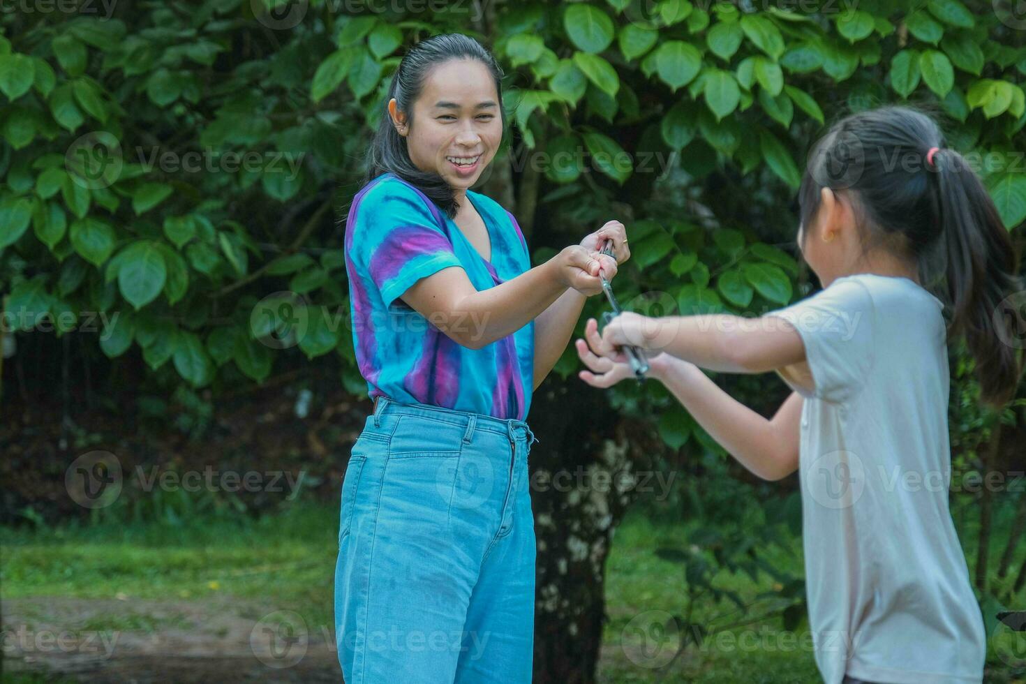 Family camping outdoor, child helping mother keep the tent. Mother and daughter go on an adventurous vacation trip together. Healthy lifestyle and eco-tourism. photo