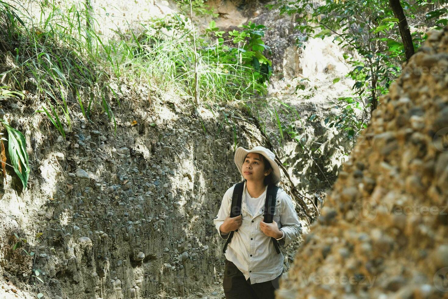 Female geologist with backpack exploring nature trail in forest and analyzing rock or gravel. Researchers collect samples of biological materials. Environmental and ecology research. photo