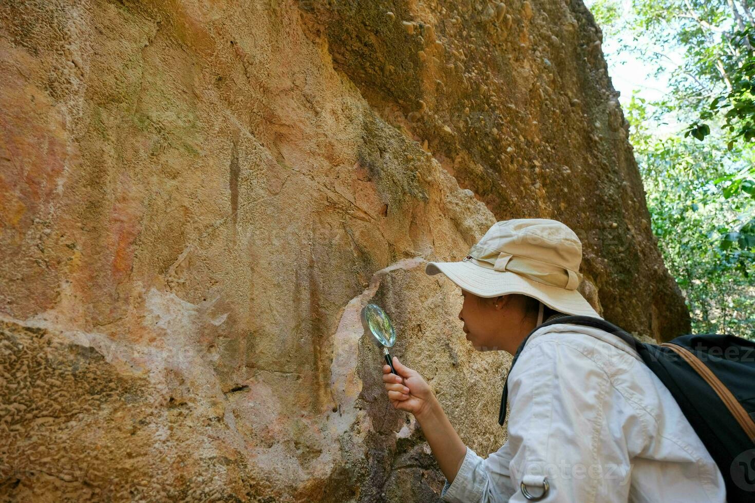 Female geologist using a magnifying glass examines nature, analyzing rocks or pebbles. Researchers collect samples of biological materials. Environmental and ecology research. photo