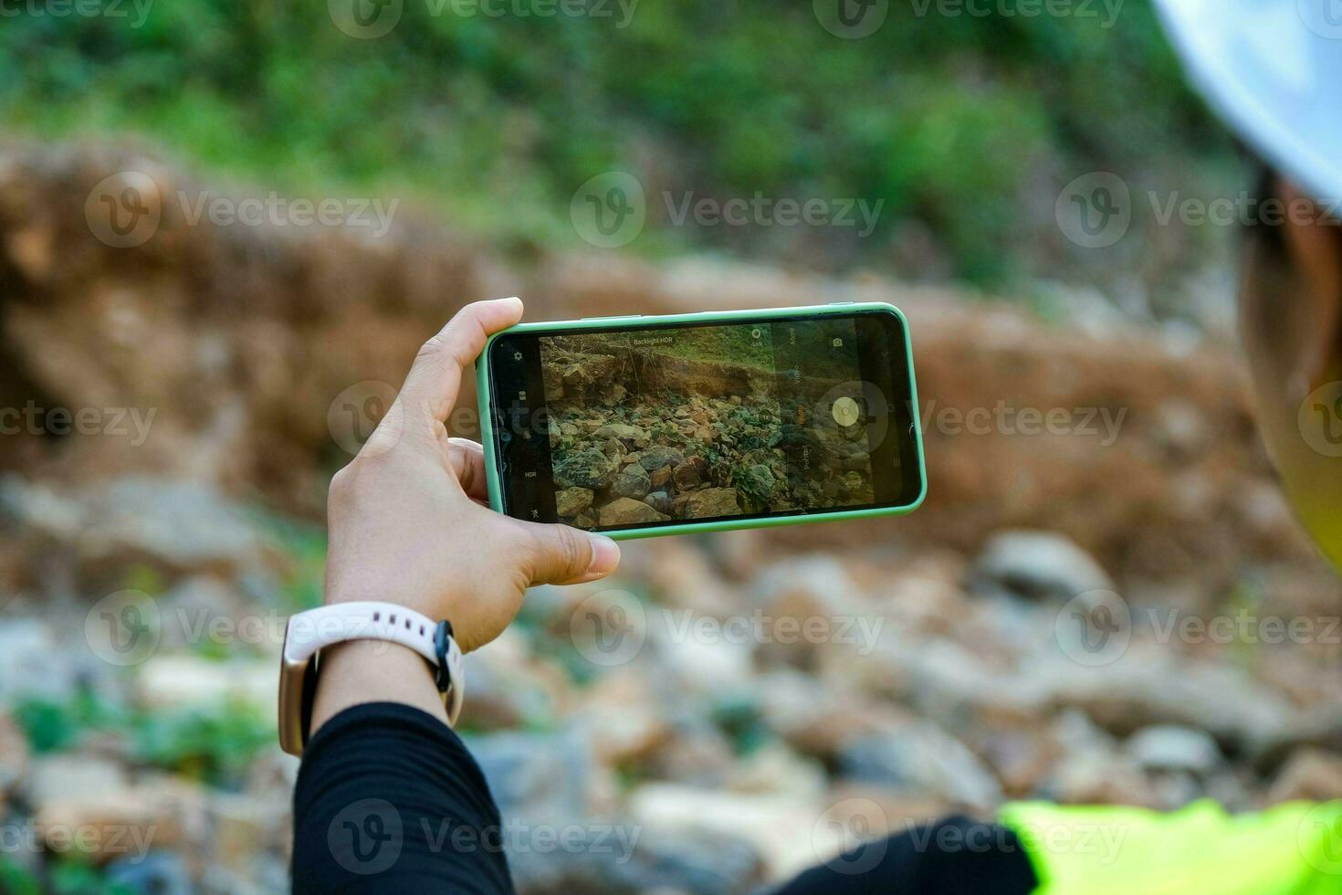 Female geologist using mobile phone to take pictures, examine nature and analyze rocks or pebbles. Researchers collect samples of biological materials. Environmental and ecology research. photo