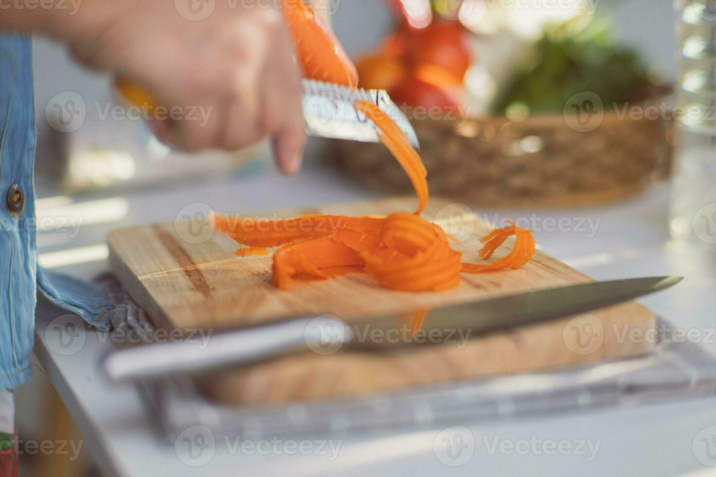 Cooking - Chef's hands are peeling carrots in the kitchen. Preparing pork stock with vegetables roth in a pot. Homemade bouillon recipe. photo