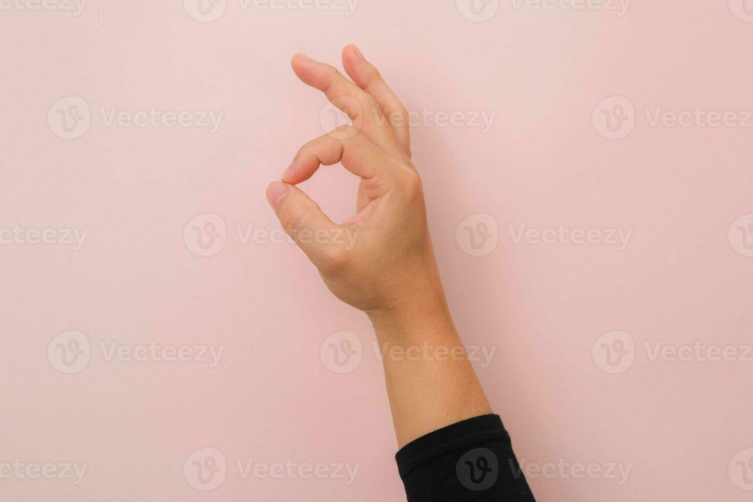 Female hand showing okay gesture isolated on pink background. photo