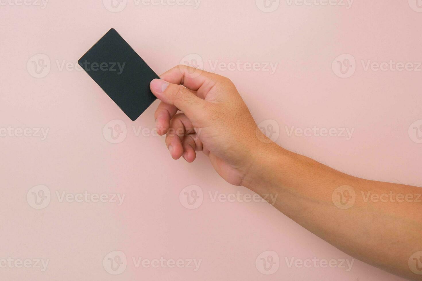 Close up of woman's hand holding blank black card isolated on pink background. photo