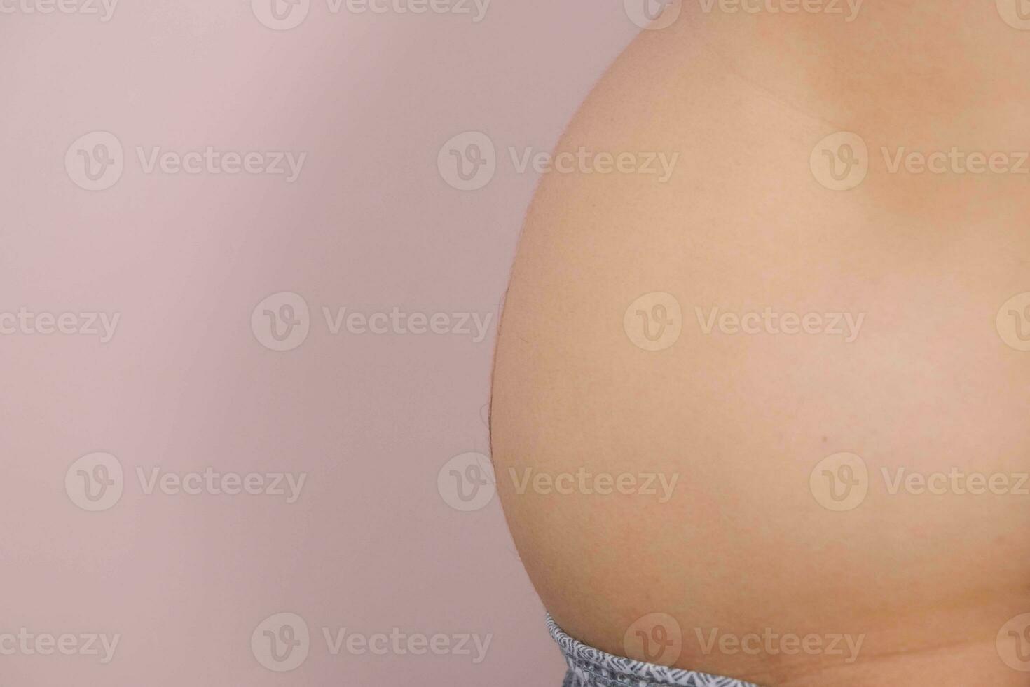 hombre demostración su grasa barriga aislado en rosado antecedentes. exceso de peso joven hombre con grande barriga foto