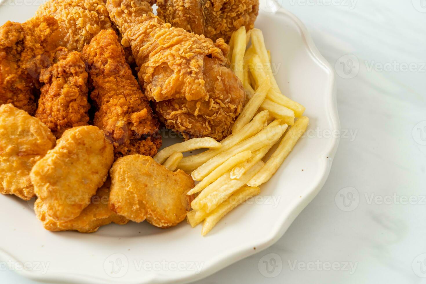 pollo frito con papas fritas y nuggets en un plato foto