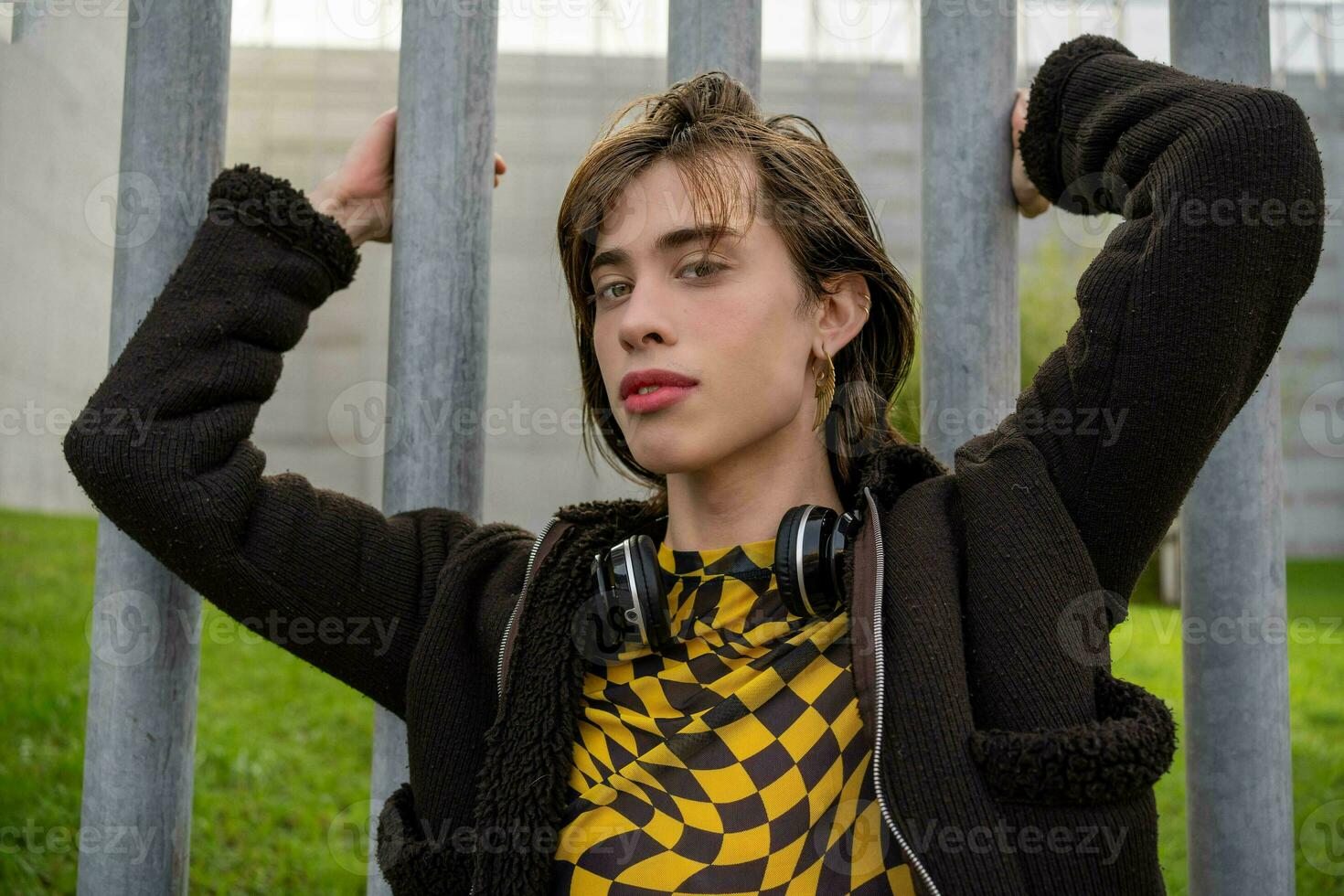 close-up of young man with clothes with bright colors and wireless headphones on his neck looking at the camera photo