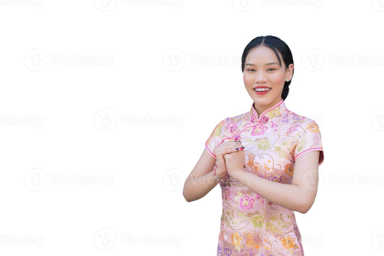 hermosa asiático mujer con rosado largo cheongsam vestir en chino nuevo año tema mientras ella muestra su mano como chino saludo mientras aislado blanco antecedentes. foto