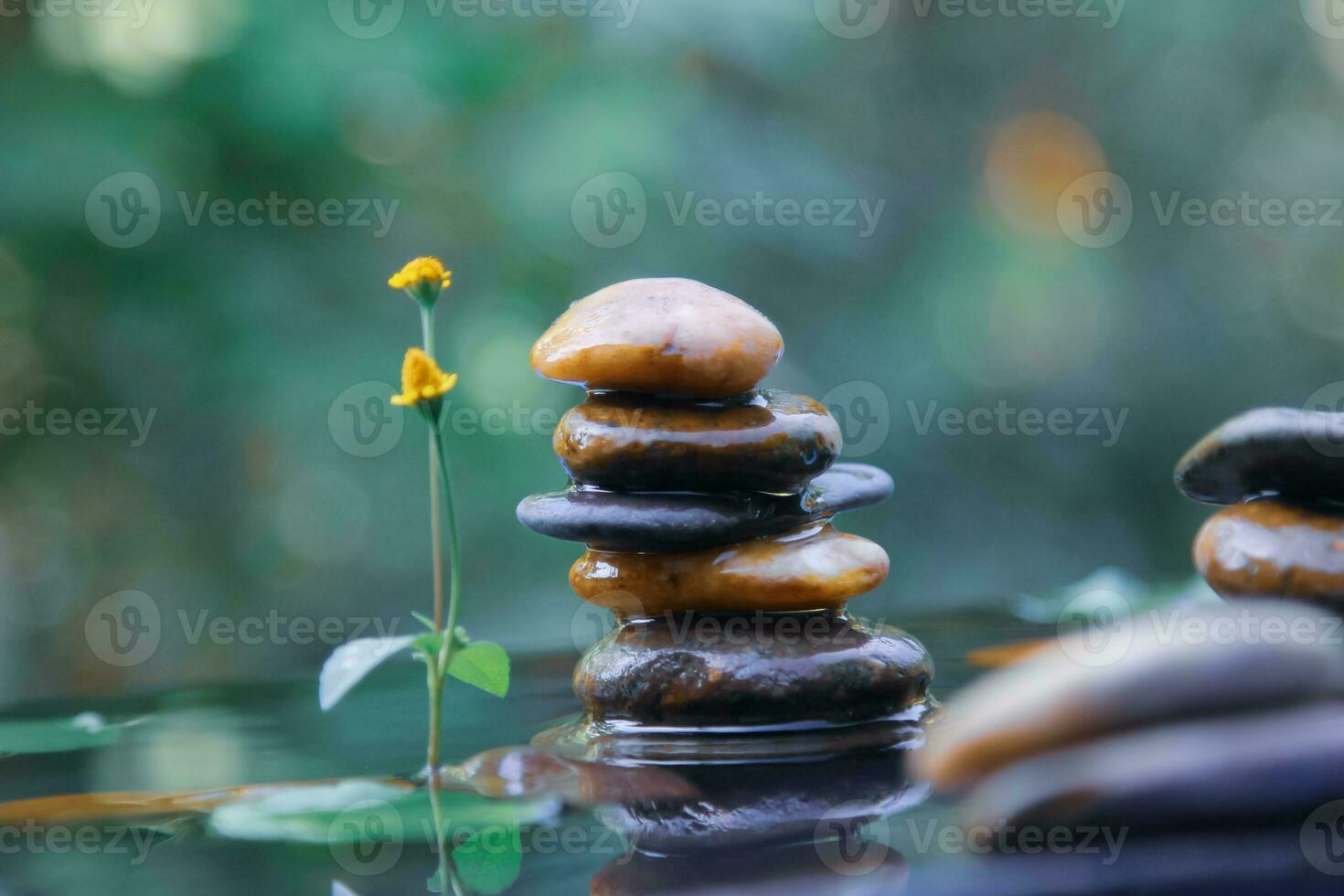 Stack of Balanced rocks pyramid on water with Golden light natural peace concepts bokeh on background photo