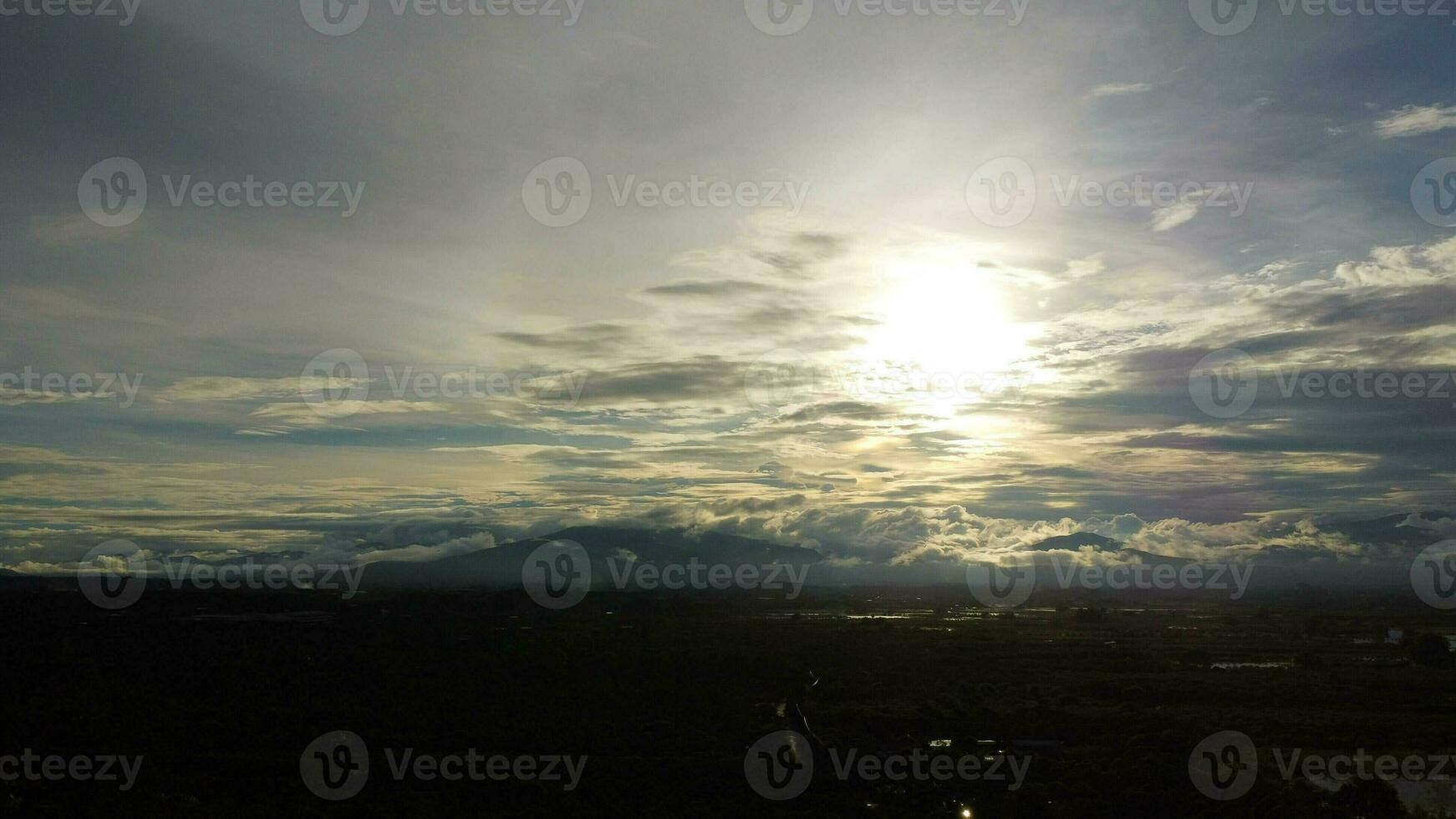 Aerial view of the flooded agricultural fields against the background of the shadows of the mountains and the overcast sky at dusk. Beautiful nature of storm clouds in the daytime. photo