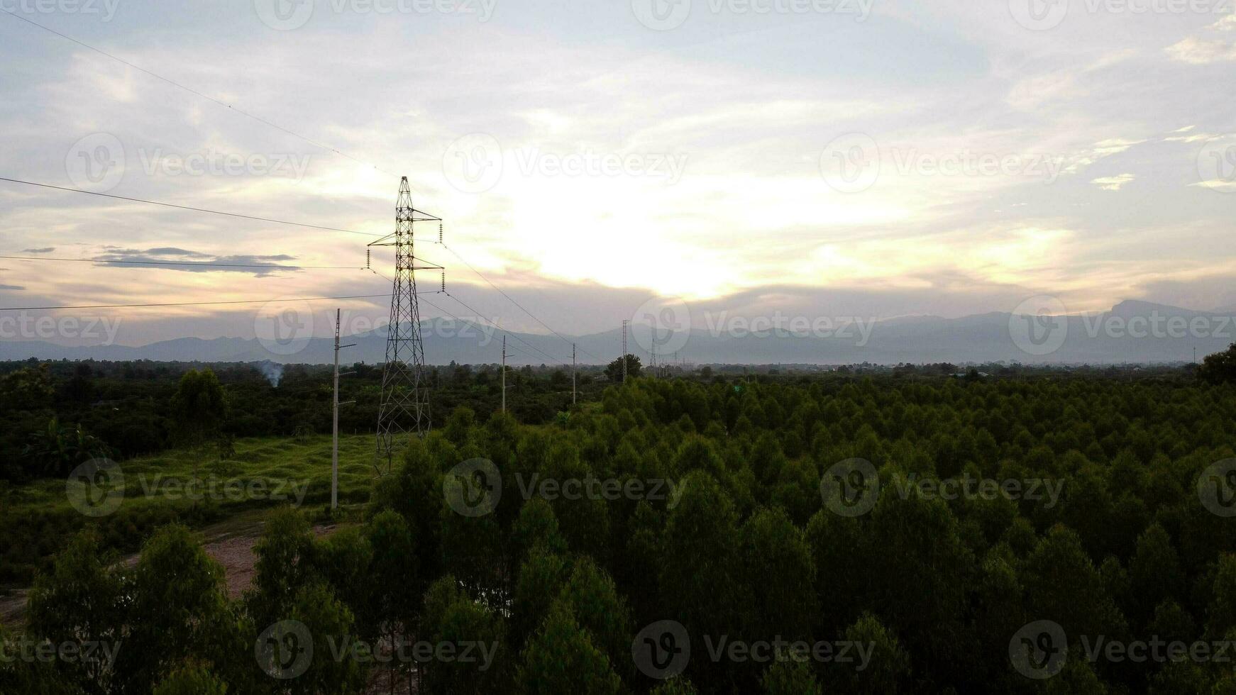 Aerial view of high voltage pylons and wires in the sky at sunset in the countryside. Drone footage of electric poles and wires at dusk. photo