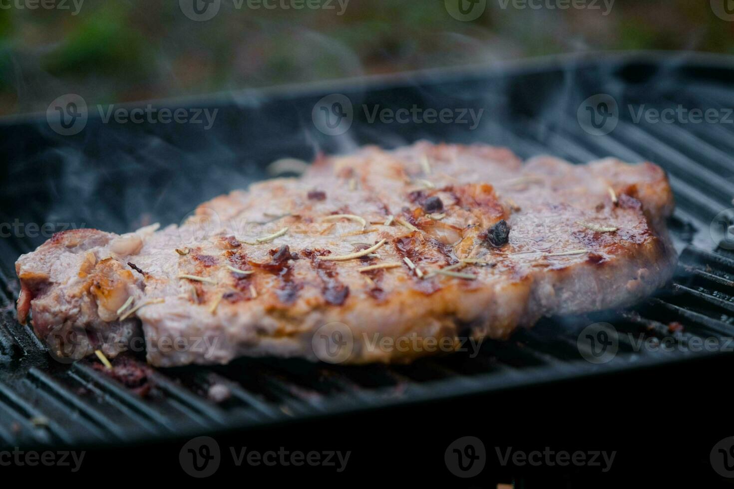 Grilled beef steak with spices on the grill with smoke. photo