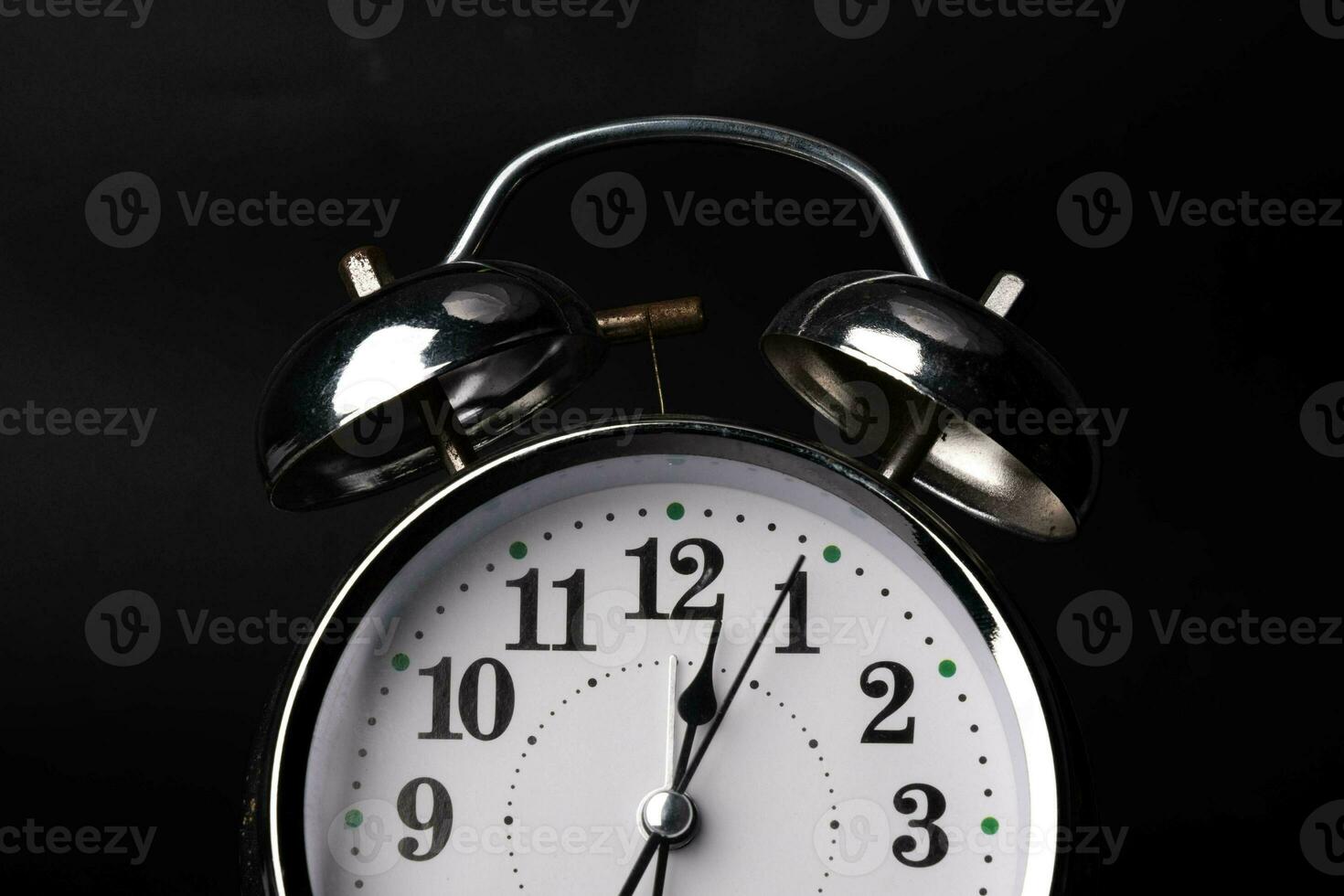 Close-up of a retro alarm clock face on a black background. Clock hands move fast, the beginning of time. photo