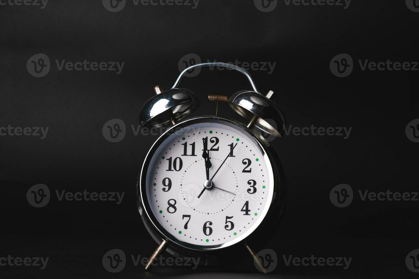 Close-up of a retro alarm clock face on a black background. Clock hands move fast, the beginning of time. photo