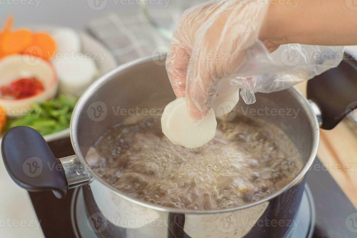 Homemade bouillon recipe. Chef's hands preparing pork rib stock  with vegetables in the pot. Cook in the kitchen. photo