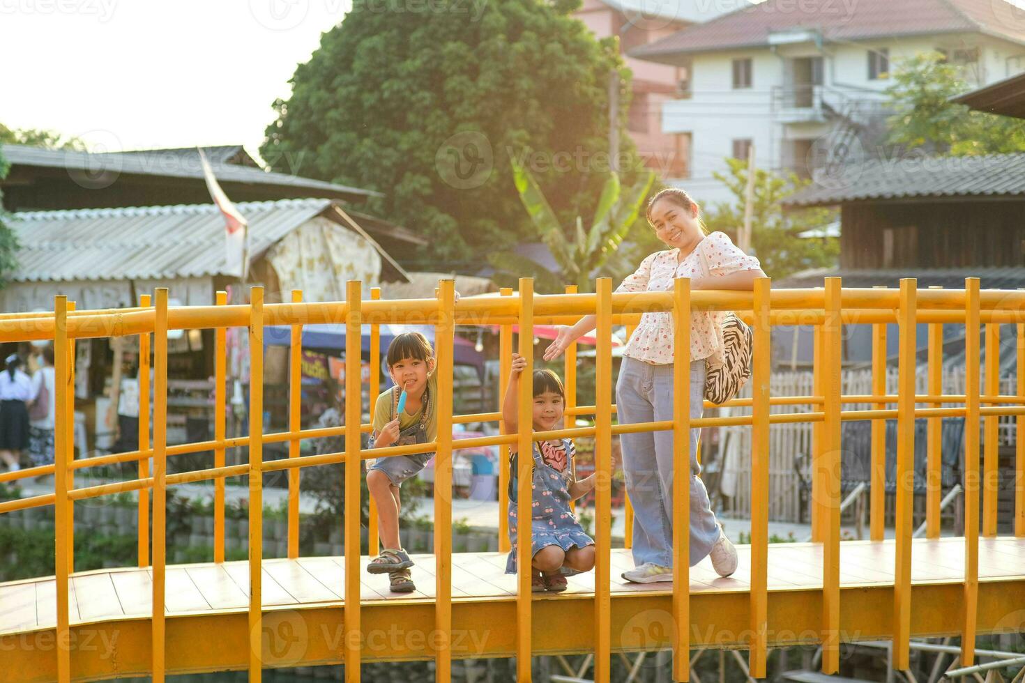 Mother and children pose smiling and looking at the camera on the bridge over the river. Khlong Mae Kha, a new attraction in Chiang Mai, Thailand. photo