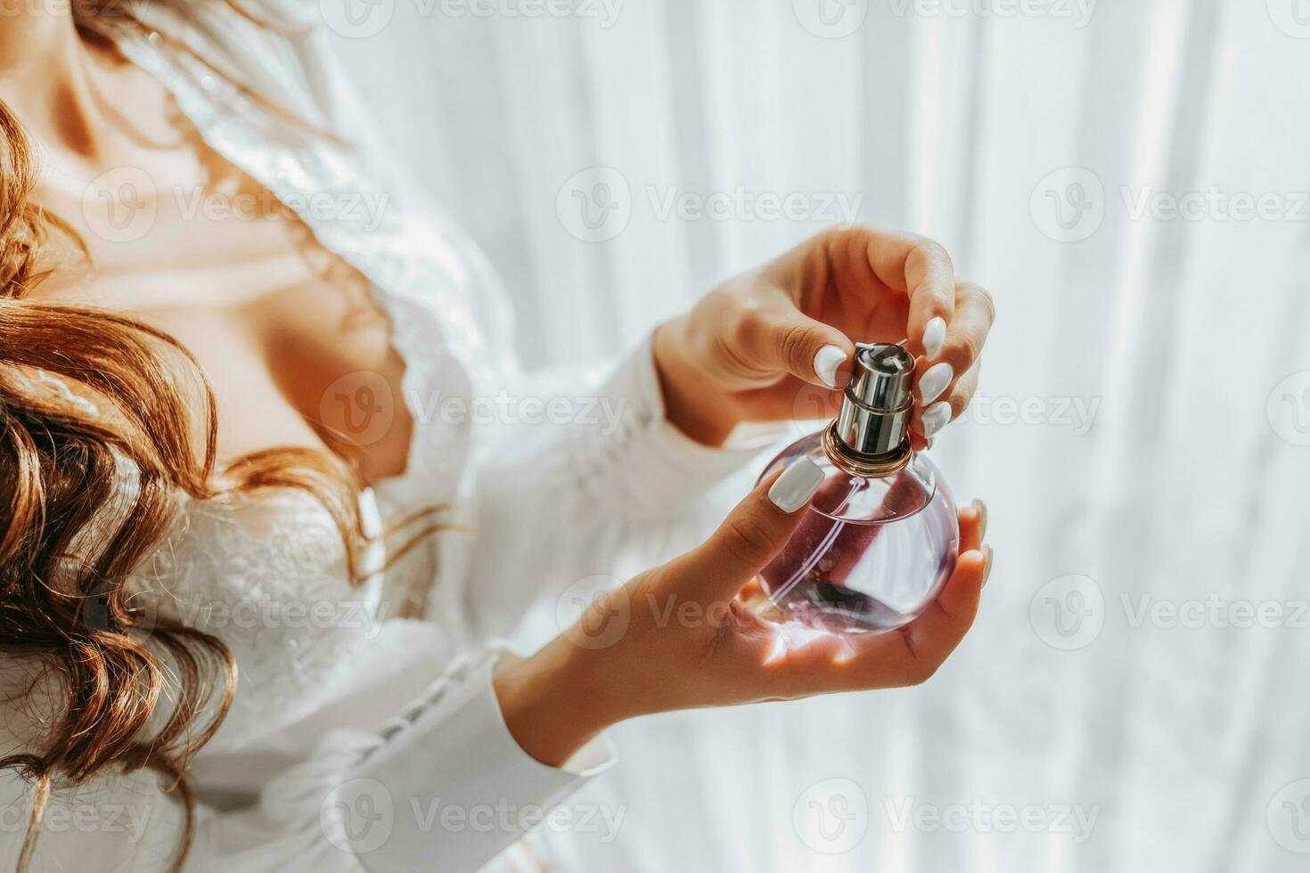 a girl in a white open dress holds purple perfume in her hands. Close-up photo