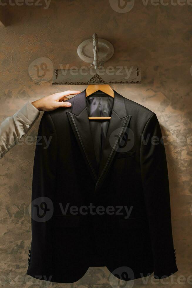 black jacket hanging indoors, businessman's hand holding black jacket photo