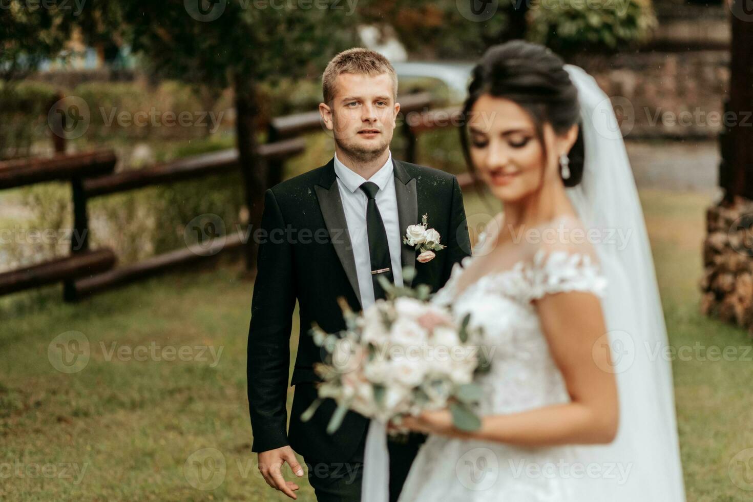 Portrait of the bride and groom in motion, the groom in a black suit is in focus walking towards the bride photo