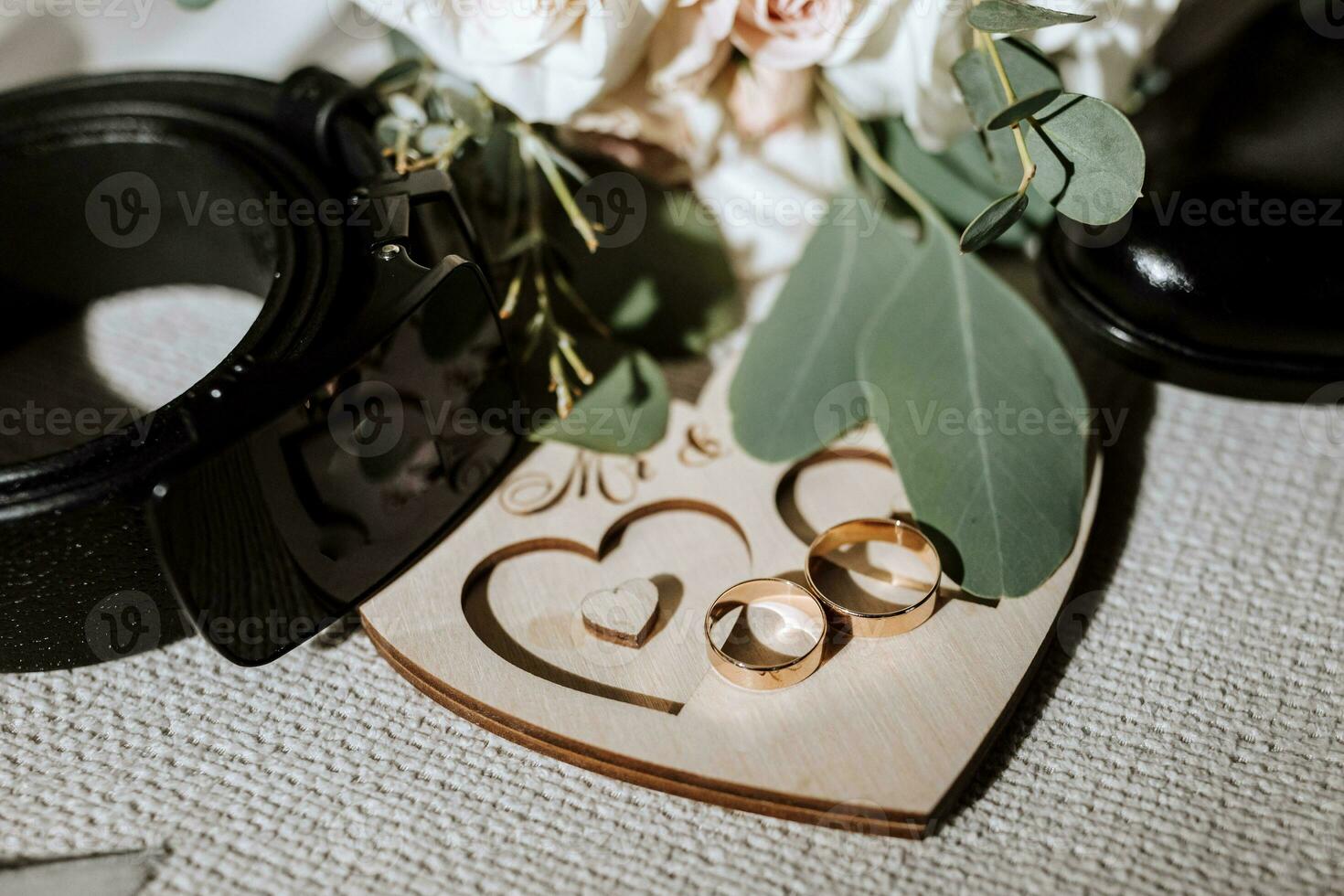 details of the groom are arranged in a composition. Black shoes, wedding bouquet, gold wedding rings on a wooden stand, black men's belt photo