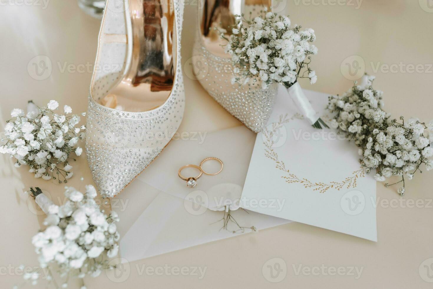 Wedding rings of the bride and groom with wedding bouquets of white flowers. Two beautiful gold wedding rings. Men's and women's rings with ornaments. Women's high-heeled shoes. place for text photo