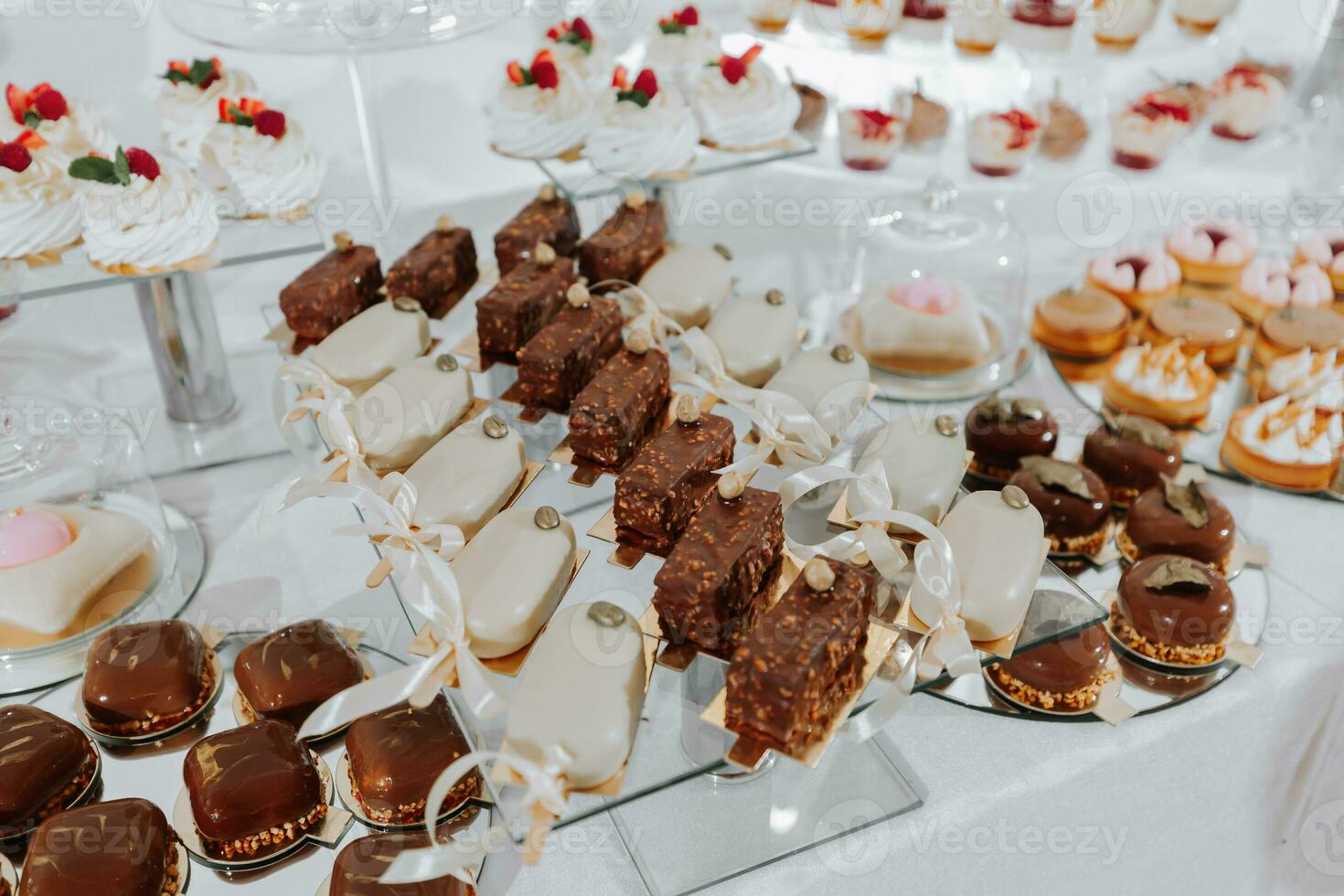 Festive dessert table with sweets. Wedding candy bar, various cakes, chocolates on stands. photo