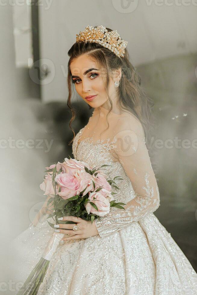 A young princess in an expensive luxurious dress with a gilded tiara on her head is standing and looking at the camera. Stylish fashion photo