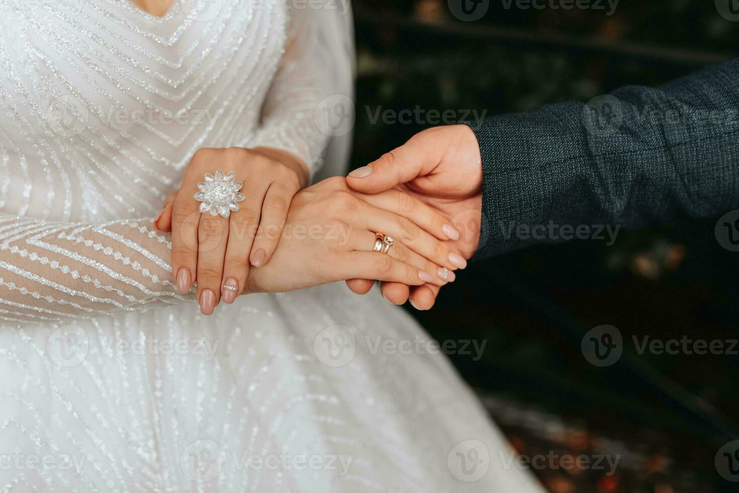 Details Wedding accessories. The bride is holding a white rose, a beautiful wedding ring with a crystal on her hand. Cropped photo. Beautiful hands photo