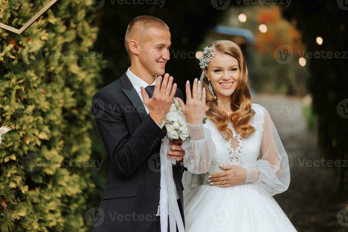 A young wedding couple at a wedding painting ceremony. The bride and groom show their wedding rings to the guests photo