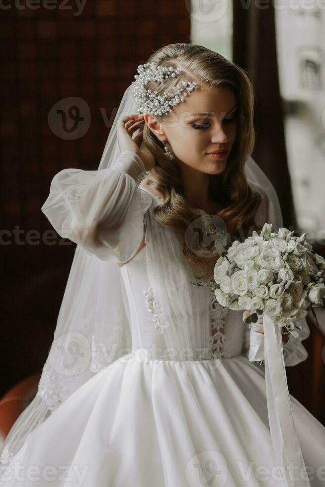 portrait of a blonde bride in a wedding dress with sleeves and a bouquet of flowers in her hands photo