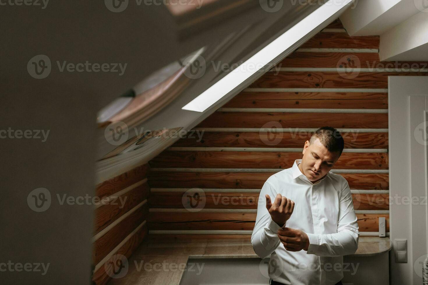 The groom is getting dressed and preparing for the wedding ceremony in a luxurious hotel room photo