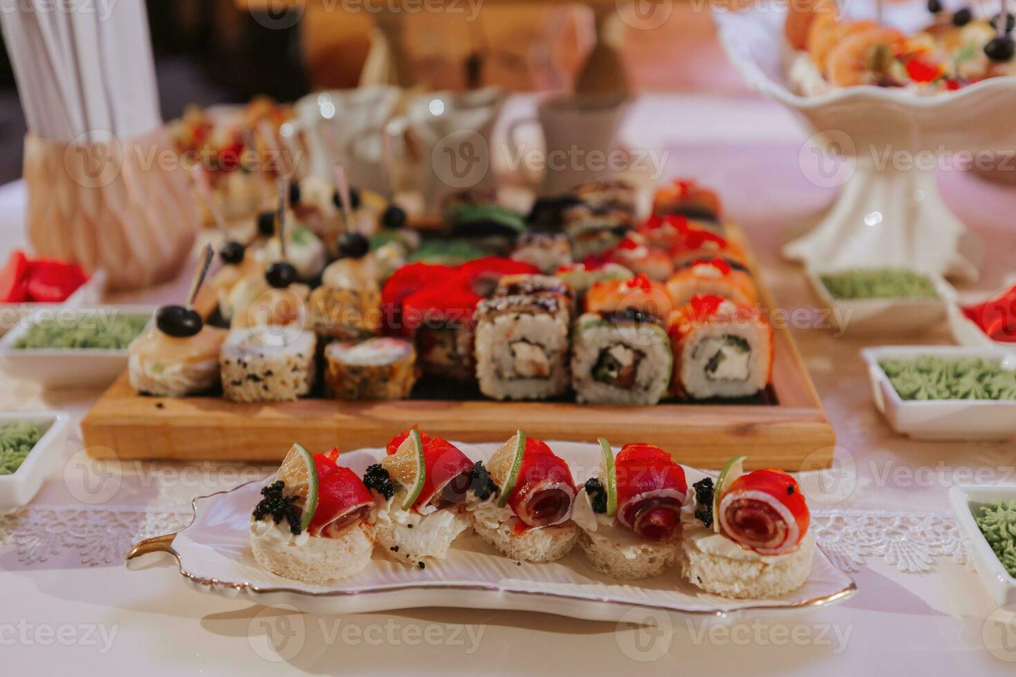 Big buffet reception of different delicious food at a wedding celebration. Snacks for guests. Wedding party. Canapes, sushi, fruit, meat, drink, wine, juice. photo