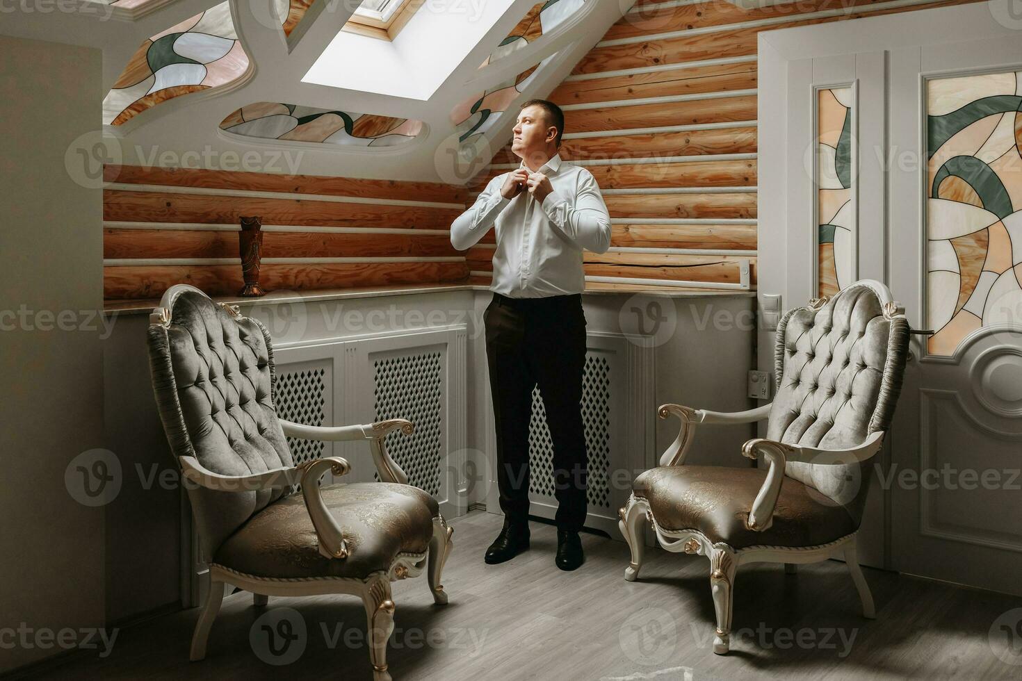 The groom is getting dressed and preparing for the wedding ceremony in a luxurious hotel room photo