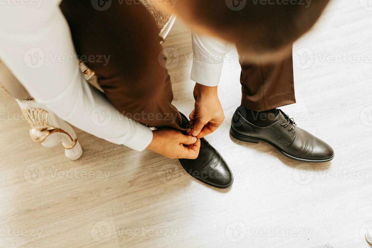 The groom is getting dressed and preparing for the wedding ceremony in a luxurious hotel room photo