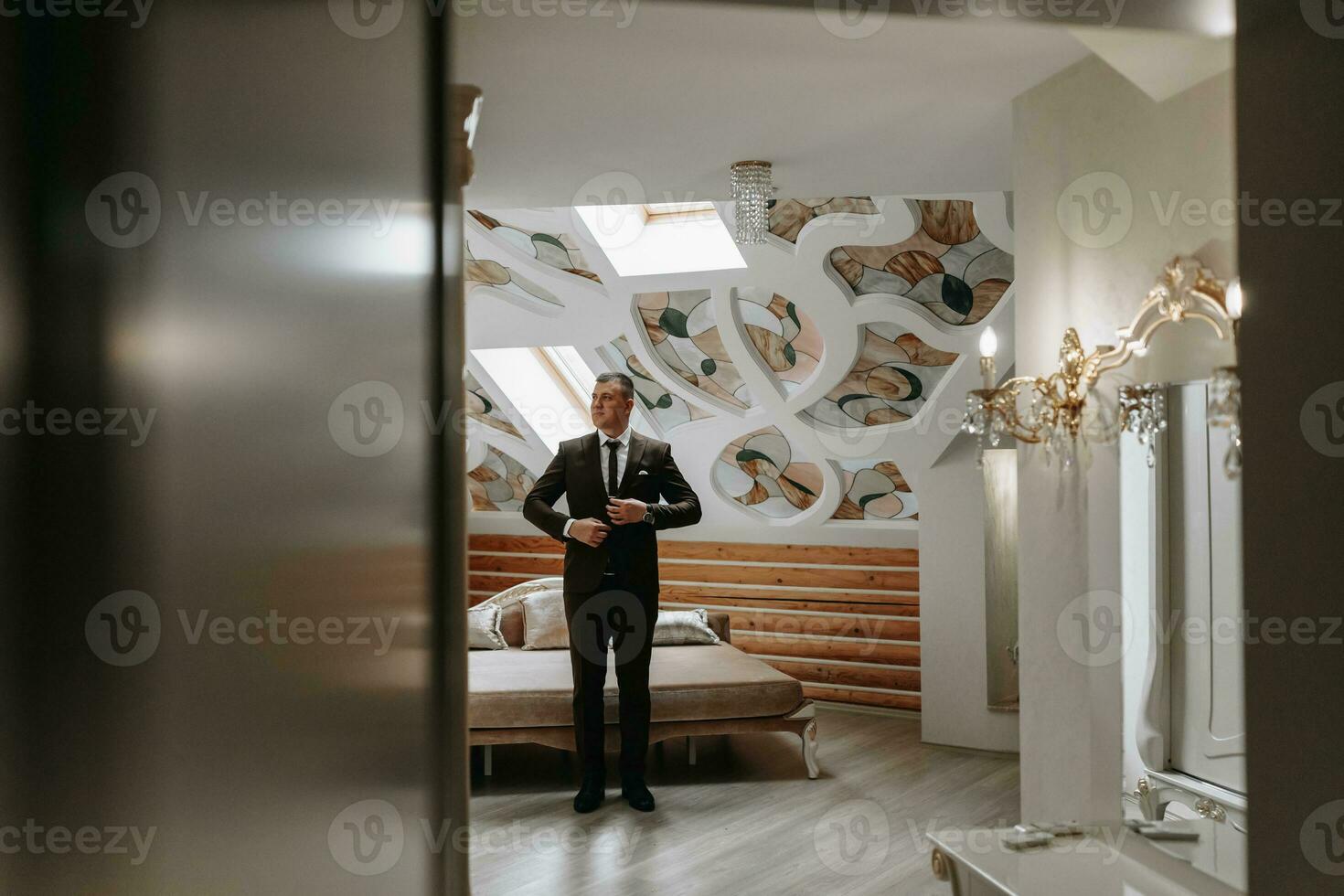 The groom is getting dressed and preparing for the wedding ceremony in a luxurious hotel room photo