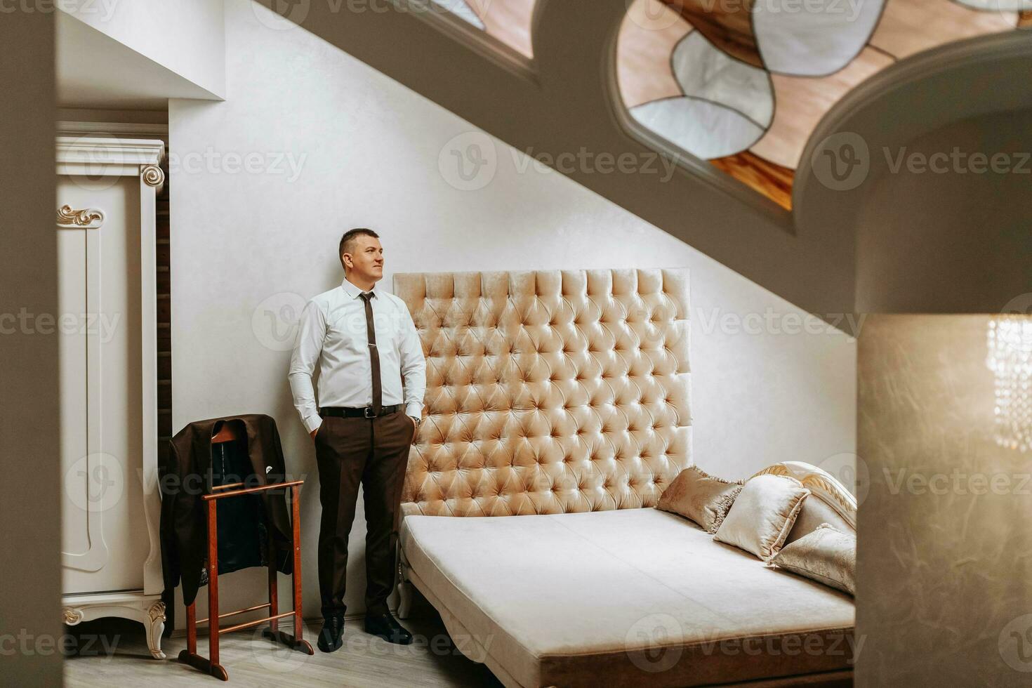 The groom is getting dressed and preparing for the wedding ceremony in a luxurious hotel room photo