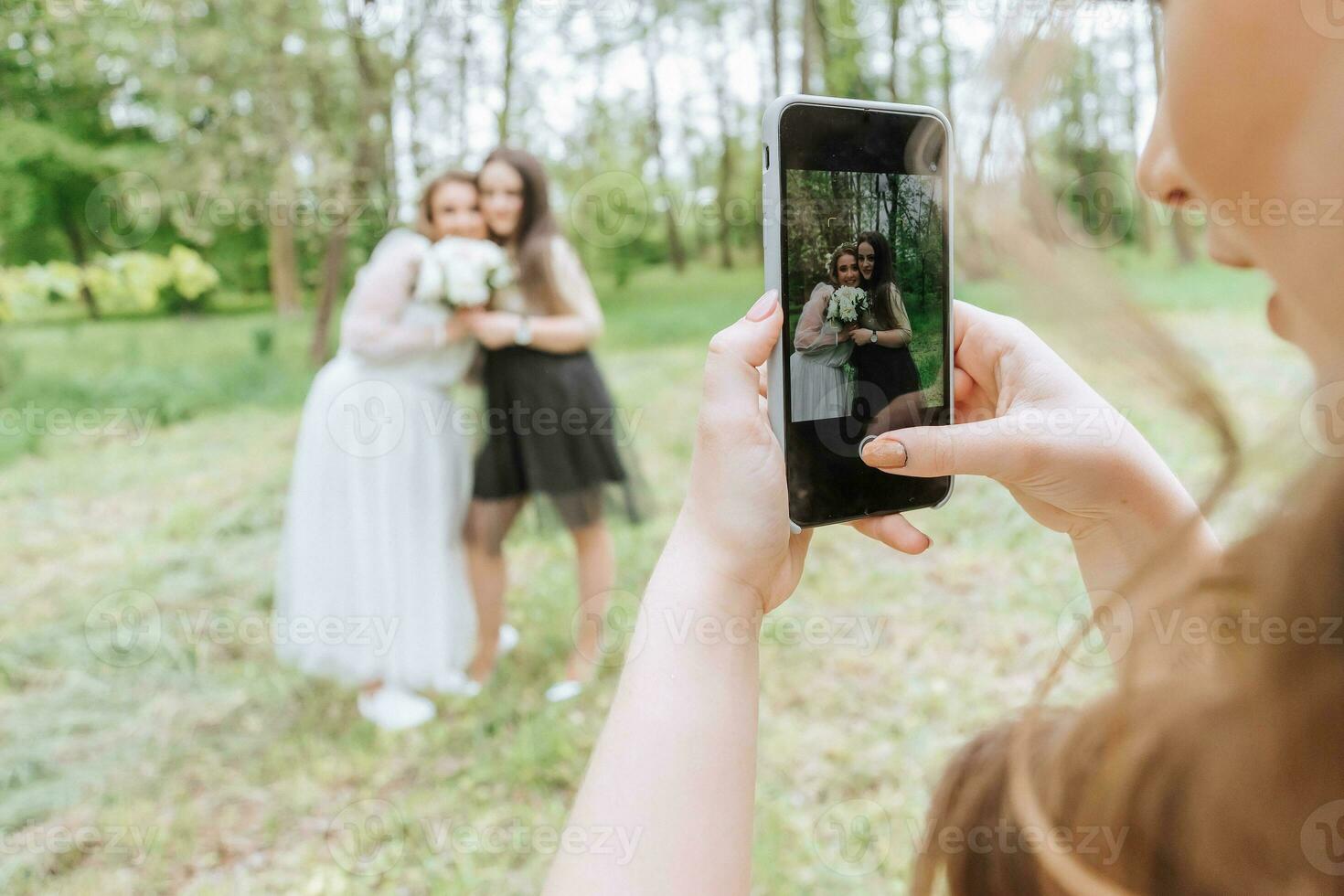 muchachas a un Boda tomar fotos en un teléfono inteligente Boda caminar en el bosque