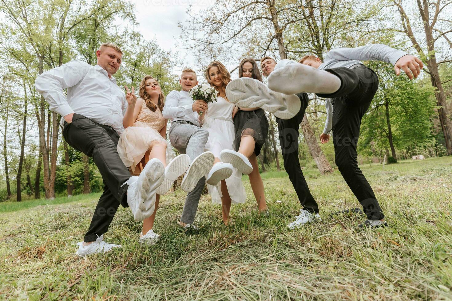 Wedding walk in the forest. Brides and their friends pose against the background of the forest. A large group of people are having fun at their friends' wedding photo