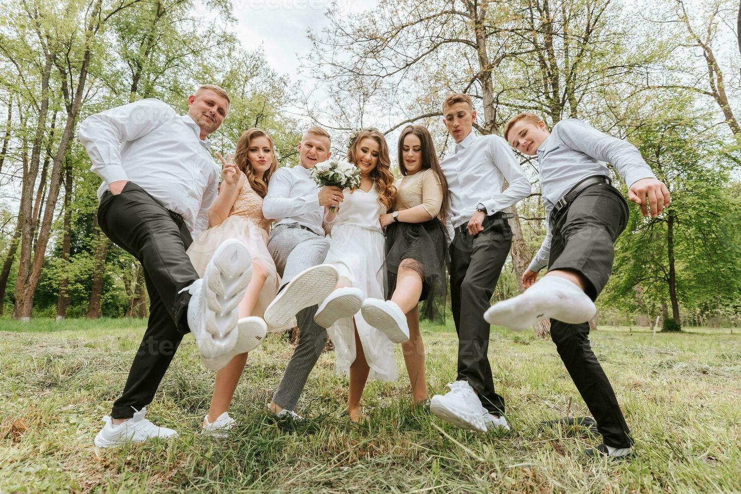 Wedding walk in the forest. Brides and their friends pose against the background of the forest. A large group of people are having fun at their friends' wedding photo